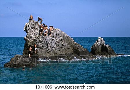 Stock Photograph - A group of men on a stack rock in the sea. Fotosearch