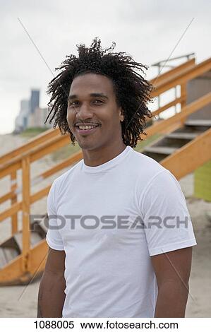 Stock Photography - A happy young man at the beach, waist up. Fotosearch