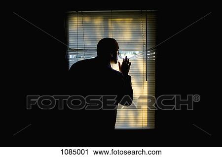 A man peeking outdoors through the blinds of a darkened room View Large Photo Image Stock Image - A man peeking outdoors through the blinds of a darkened room. Fotosearch