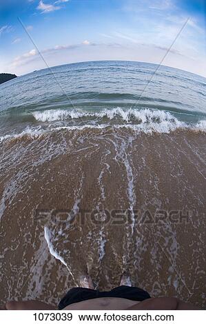 A man standing on the seashore and a view of the sea through a fish-eye lens View Large Photo Image Stock Photo - A man standing on the seashore and a view of the sea through a fish-eye lens. Fotosearch