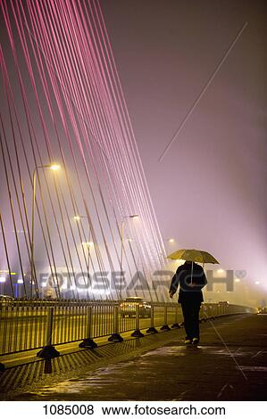 A man walking along a city street, holding an umbrella View Large Photo Image Stock Photo - A man walking along a city street, holding an umbrella. Fotosearch