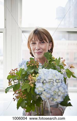 A mature woman holding a flower arrangement with Hydrangeas View Large Photo Image Picture - A mature woman holding a flower arrangement with Hydrangeas. Fotosearch