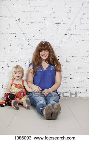 A mother and her young daughter sitting side by side against a brick wall View Large Photo Image Stock Image - A mother and her young daughter sitting side by side against a brick wall. Fotosearch