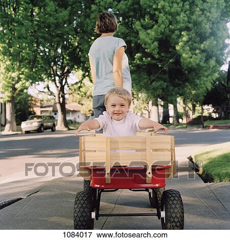 A mother pulling her young son in a wagon, focus on boy View Large Photo Image Stock Photo - A mother pulling her young son in a wagon, focus on boy. Fotosearch