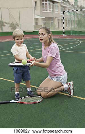 Stock Photo - A mother teaching her son how to balance a tennis ball on a racket. Fotosearch