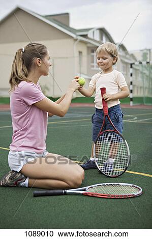 Stock Image - A mother teaching her young son tennis. Fotosearch