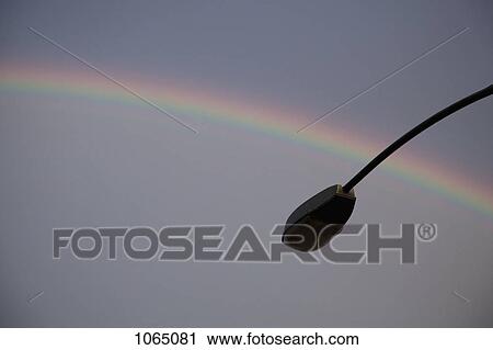 Stock Image - A rainbow in back of a silhouetted street lamp. Fotosearch