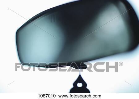 Stock Image - A rearview mirror with an air freshener hanging from it, close-up. Fotosearch