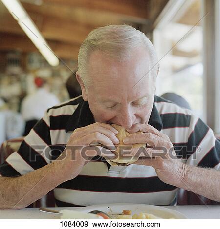 A senior man eating a hamburger View Large Photo Image Stock Photo - A senior man eating a hamburger. Fotosearch