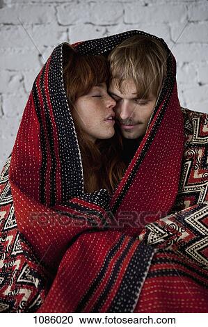 Stock Image - A sensual young couple wrapped in a blanket. Fotosearch