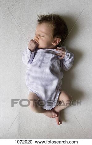 A sleeping newborn sucking on her fist View Large Photo Image Stock Image - A sleeping newborn sucking on her fist. Fotosearch