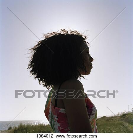 Stock Image - A teenage girl at the beach, staring at the view. Fotosearch