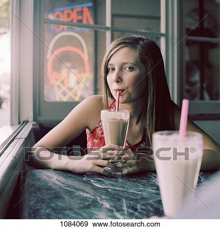 Stock Photo - A teenage girl drinking a milkshake in a diner. Fotosearch