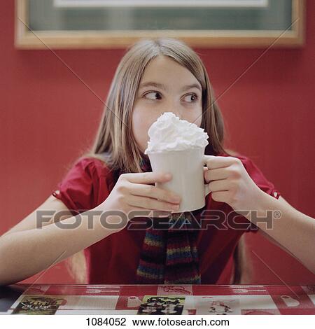 Stock Image - A teenage girl holding a mug of hot chocolate. Fotosearch