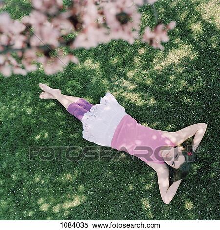 A teenage girl lying in grass with hands behind head, looking up View Large Photo Image Stock Photography - A teenage girl lying in grass with hands behind head, looking up. Fotosearch