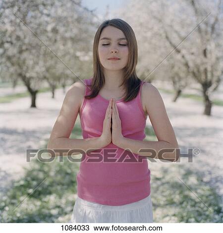 Stock Image - A teenage girl with eyes closed practicing yoga. Fotosearch