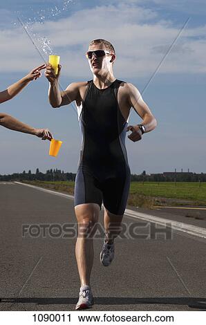 A volunteer handing out water to a runner in a race View Large Photo Image Stock Image - A volunteer handing out water to a runner in a race. Fotosearch