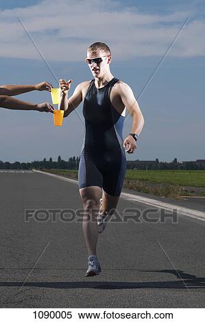 A volunteer handing out water to a runner in a race View Large Photo Image Stock Photography - A volunteer handing out water to a runner in a race. Fotosearch