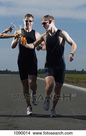 A volunteer handing water to runners in a race View Large Photo Image Picture - A volunteer handing water to runners in a race. Fotosearch