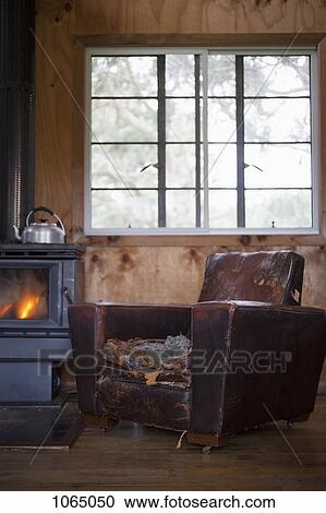 A well worn leather armchair next to a wood burning stove View Large Photo Image Stock Image - A well worn leather armchair next to a wood burning stove. Fotosearch