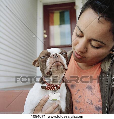 Stock Image - A woman holding her dog. Fotosearch