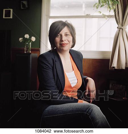 A woman sitting comfortably in a softly lit room View Large Photo Image Stock Image - A woman sitting comfortably in a softly lit room. Fotosearch