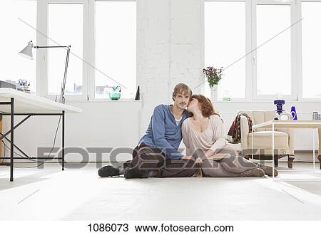 A young affectionate couple sitting side by side on the floor View Large Photo Image Stock Image - A young affectionate couple sitting side by side on the floor. Fotosearch