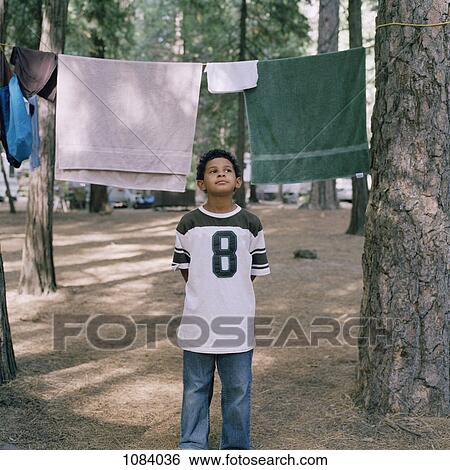 Stock Photograph - A young boy standing in front of towels on a clothesline. Fotosearch
