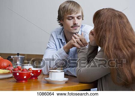 A young couple holding hands at the breakfast table View Large Photo Image Picture - A young couple holding hands at the breakfast table. Fotosearch