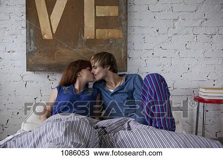 A young couple kissing in bed View Large Photo Image Stock Image - A young couple kissing in bed. Fotosearch
