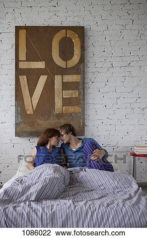 A young couple lying bed about to kiss View Large Photo Image Stock Image - A young couple lying bed about to kiss. Fotosearch