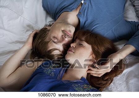 A young couple lying head to head on a bed, eyes closed View Large Photo Image Stock Image - A young couple lying head to head on a bed, eyes closed. Fotosearch