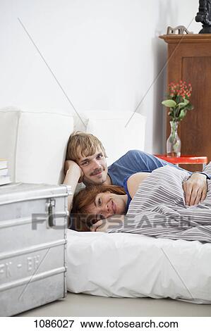 Stock Photo - A young couple lying in bed. Fotosearch