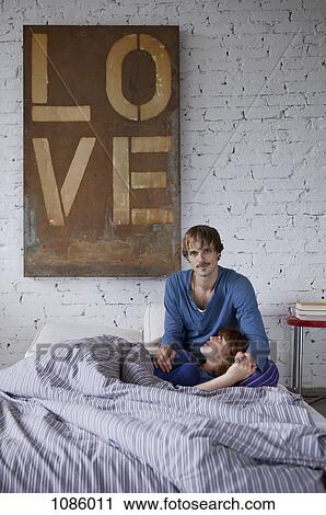 Stock Image - A young couple relaxing in bed. Fotosearch