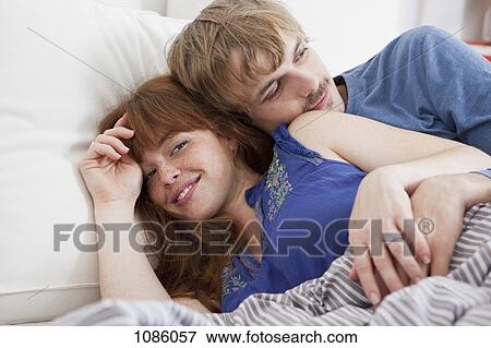 A young couple snuggling in bed View Large Photo Image Stock Photo - A young couple snuggling in bed. Fotosearch