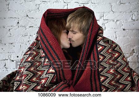 A young couple wrapped in a blanket kissing View Large Photo Image Stock Photo - A young couple wrapped in a blanket kissing. Fotosearch