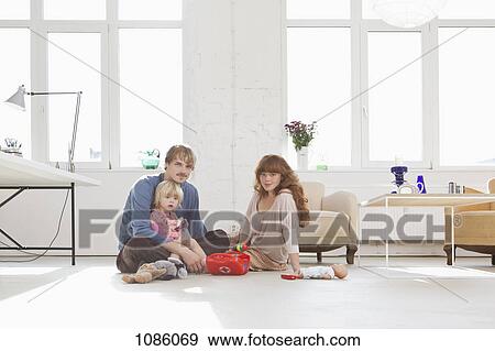 Stock Photo - A young family playing with toys on the living room floor. Fotosearch