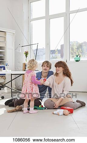 A young girl and her parents playing with toys View Large Photo Image Stock Photograph - A young girl and her parents playing with toys. Fotosearch