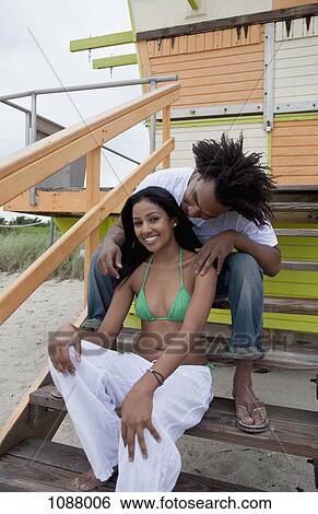 A young happy couple sitting on a staircase at the beach View Large Photo Image Stock Photograph - A young happy couple sitting on a staircase at the beach. Fotosearch