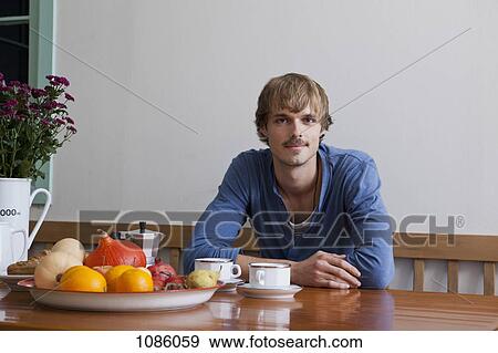 A young man having breakfast, looking at camera View Large Photo Image Stock Photo - A young man having breakfast, looking at camera. Fotosearch