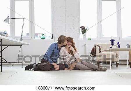 A young man kissing his girlfriend, side by side, sitting on floor View Large Photo Image Stock Photo - A young man kissing his girlfriend, side by side, sitting on floor. Fotosearch