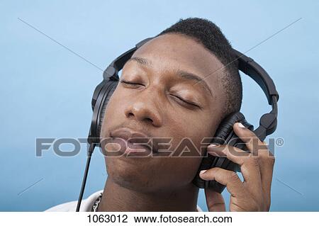 A young man listening to music with headphones, eyes closed View Large Photo Image Stock Image - A young man listening to music with headphones, eyes closed. Fotosearch