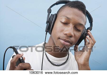 Stock Photograph - A young man listening to music with headphones, eyes closed. Fotosearch