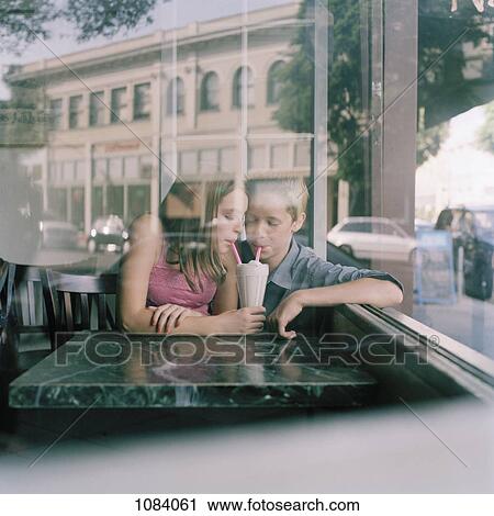 A young teenage couple sharing a milkshake at a diner, viewed through window View Large Photo Image Stock Image - A young teenage couple sharing a milkshake at a diner, viewed through window. Fotosearch