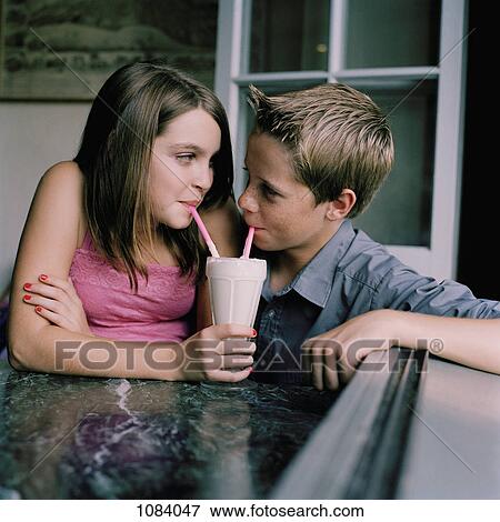 Stock Photo - A young teenage couple sharing a milkshake at a diner. Fotosearch