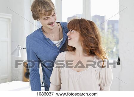 Stock Photo - A young woman looking up at her boyfriend standing behind her. Fotosearch