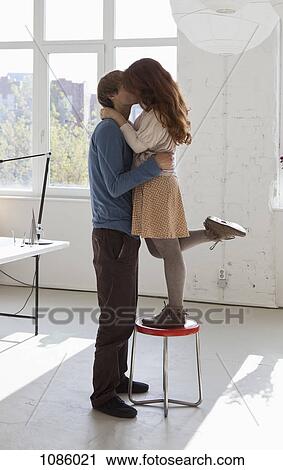 A young woman on a stool kissing her tall boyfriend View Large Photo Image Stock Image - A young woman on a stool kissing her tall boyfriend. Fotosearch