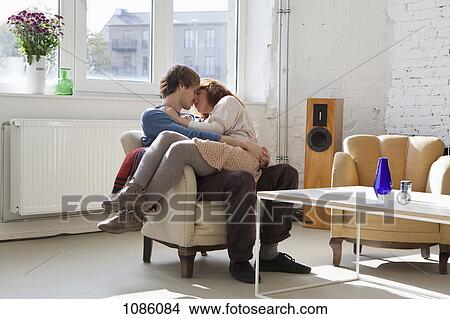 A young woman sitting on her boyfriend's lap, kissing View Large Photo Image Picture - A young woman sitting on her boyfriend's lap, kissing. Fotosearch
