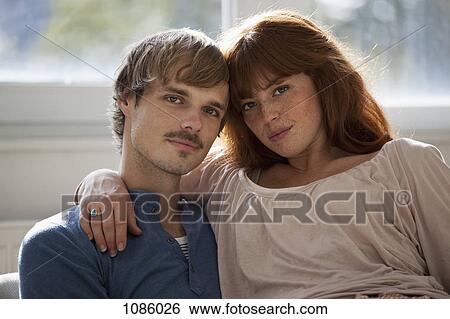 Stock Photograph - A young woman sitting on her boyfriend's lap. Fotosearch