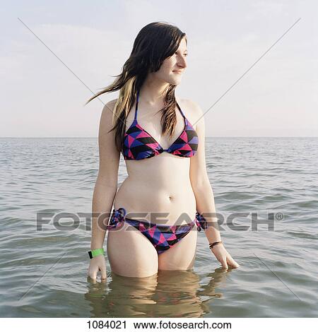 A young woman standing in the sea, looking away View Large Photo Image Stock Image - A young woman standing in the sea, looking away. Fotosearch